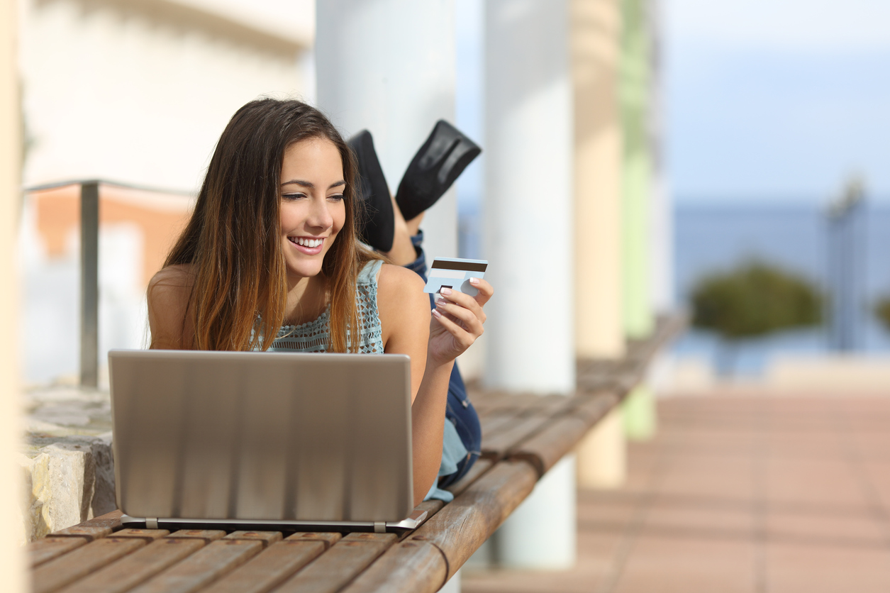 aprenda-ganhe-dinheiro-com-milhas Imagem mostra mulher com notebook e cartão de crédito nas mãos para compras online e acumular e venda de milhas aéreas