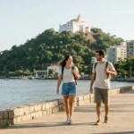 Viajantes na orla de Vila Velha durante uma viagem ao Espírito Santo, com o Convento da Penha ao fundo