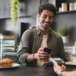 Como pagar Pix com pontos Livelo e avaliar se o resgate compensa - Pessoa usando o celular para pagar Pix com pontos Livelo